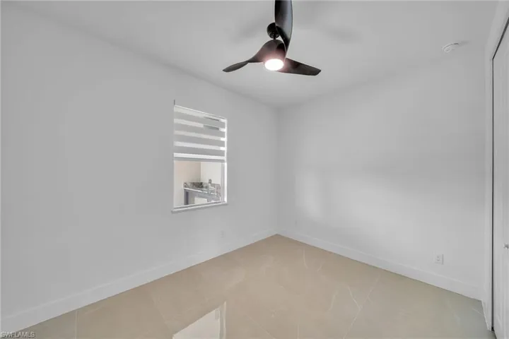 Empty room with light tile patterned floors and ceiling fan