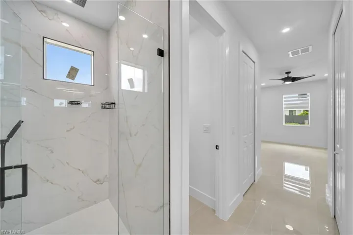 Bathroom featuring ceiling fan and a shower with shower door
