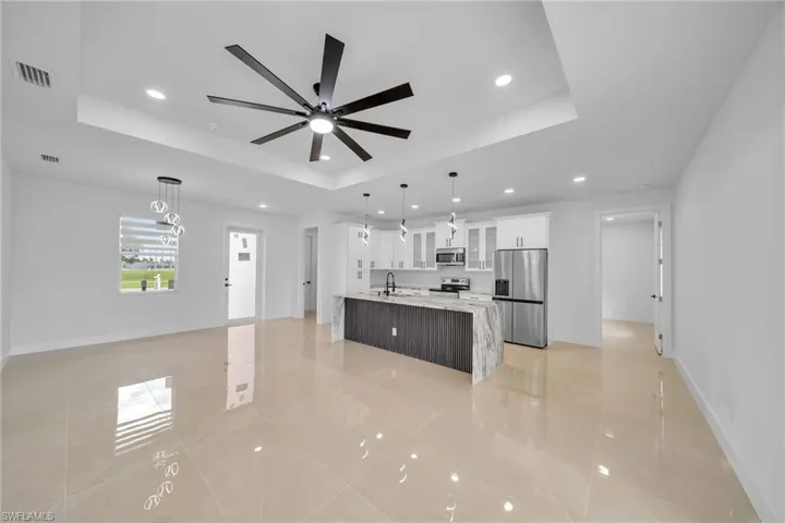 Kitchen featuring stainless steel appliances, white cabinetry, a raised ceiling, and decorative light fixtures