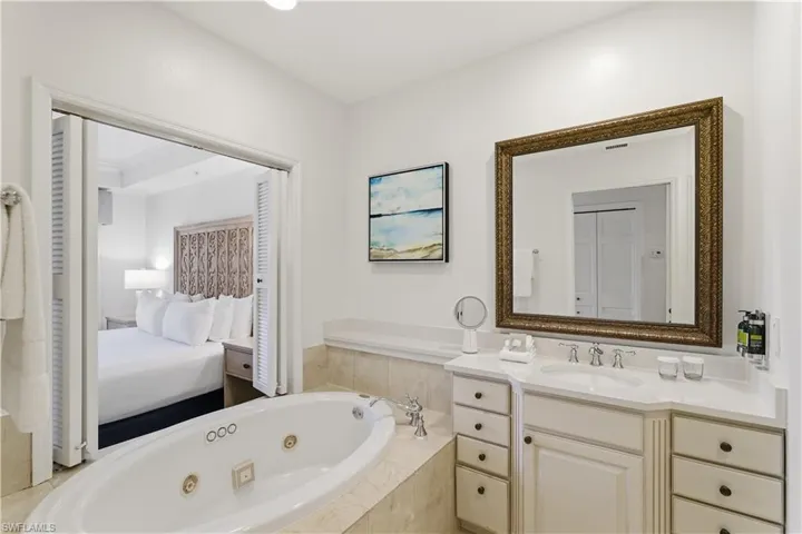 Full bathroom featuring a whirlpool tub, vanity, connected bathroom, and a closet