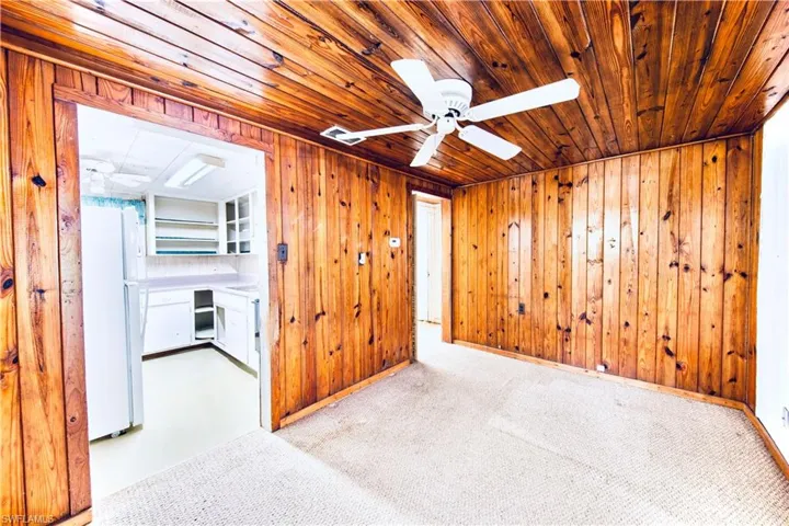 Spare room with ceiling fan, wood ceiling, carpet floors, wood walls, and built in study area