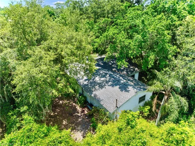 Aerial view of property and surrounding area with a forest