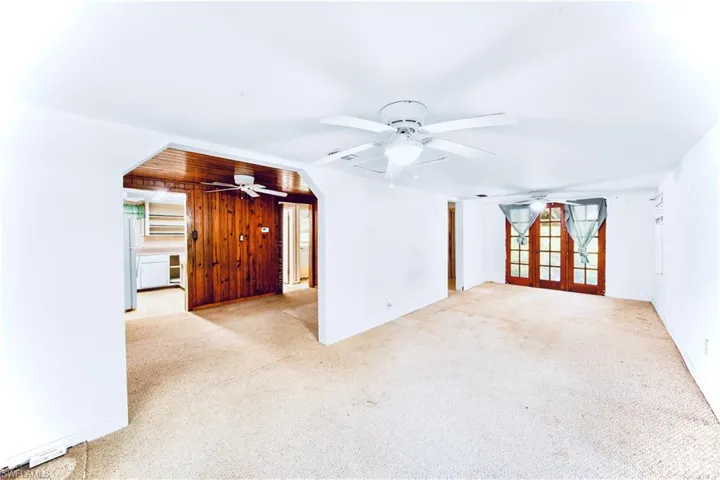 Spare room featuring carpet flooring, french doors, and wood walls