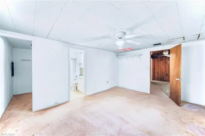 Unfurnished bedroom featuring carpet, ensuite bath, a ceiling fan, and a closet