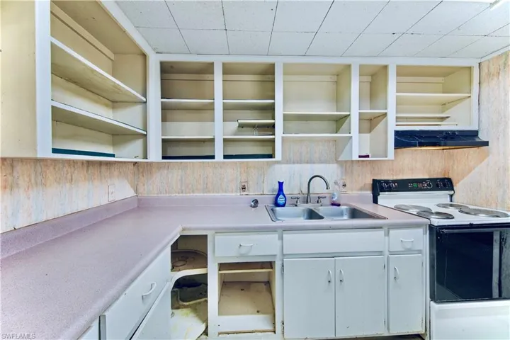 Kitchen featuring open shelves, white electric range, light countertops, and exhaust hood