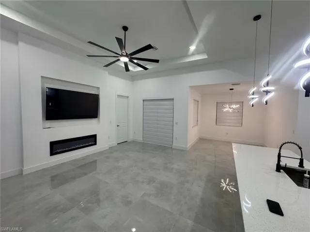 Unfurnished living room featuring ceiling fan with notable chandelier and sink
