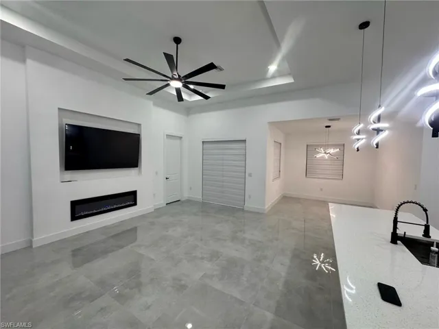 Unfurnished living room with ceiling fan with notable chandelier and sink