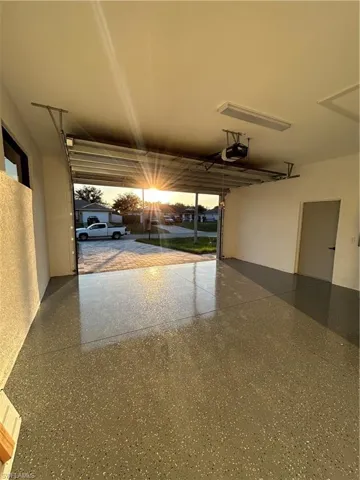 Garage at dusk featuring a garage door opener