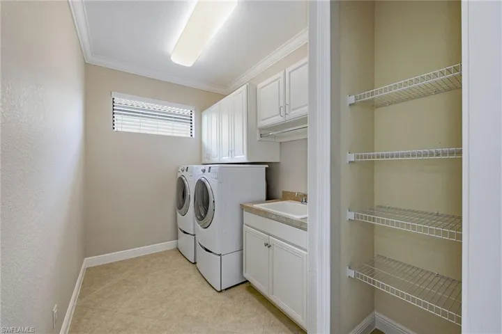 Laundry room with whirlpool washer and dryer, closet, sink and cabinetry