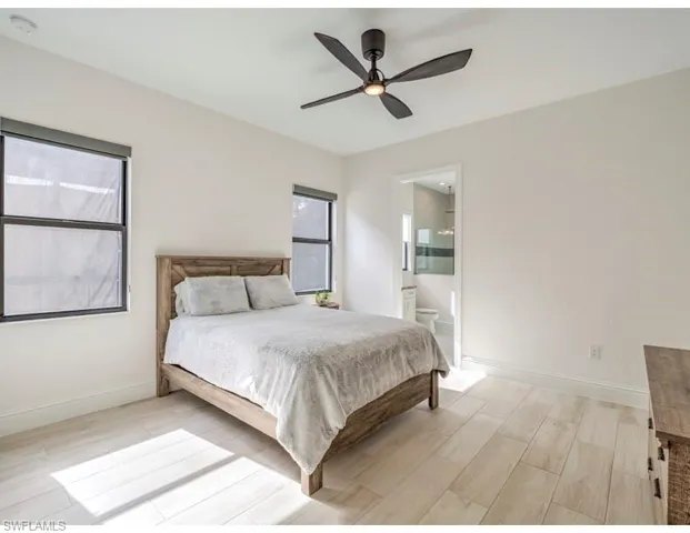 Bedroom with wood tiled floors, a ceiling fan, and ensuite bath