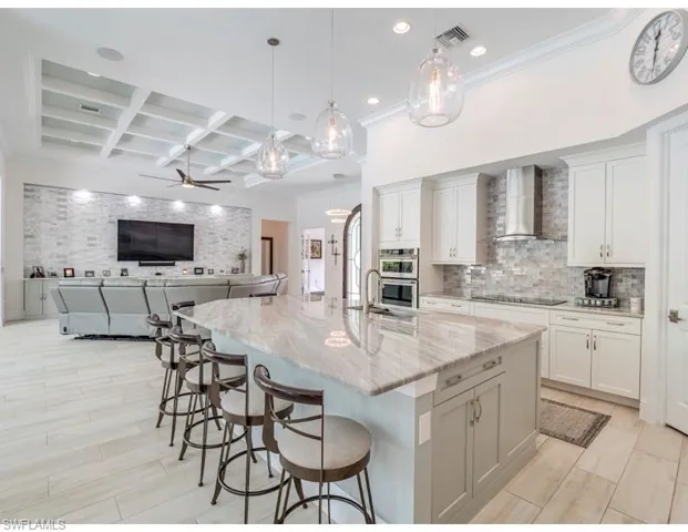 Kitchen featuring coffered ceiling, open floor plan, pendant lighting, a breakfast bar area, and beam ceiling
