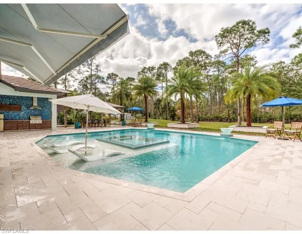 View of swimming pool with a patio area, outdoor dining area, a pool with connected hot tub, and exterior kitchen