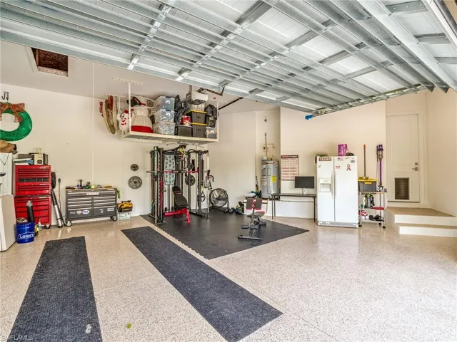 Garage with white refrigerator with ice dispenser and electric water heater