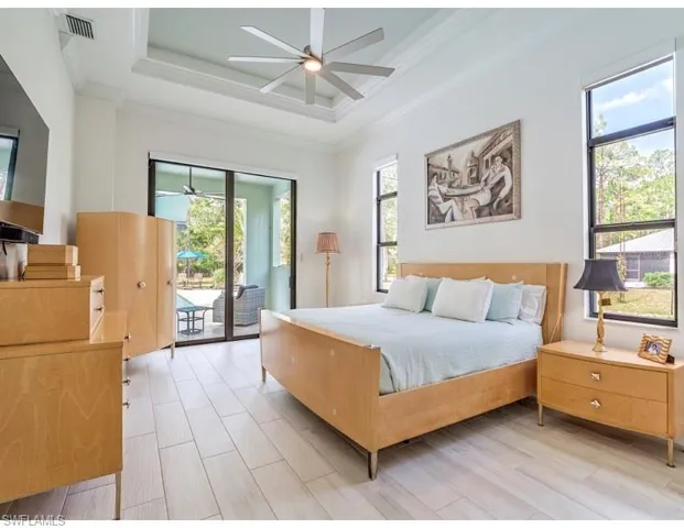 Bedroom with access to exterior, crown molding, a raised ceiling, wood finish floors, and a ceiling fan