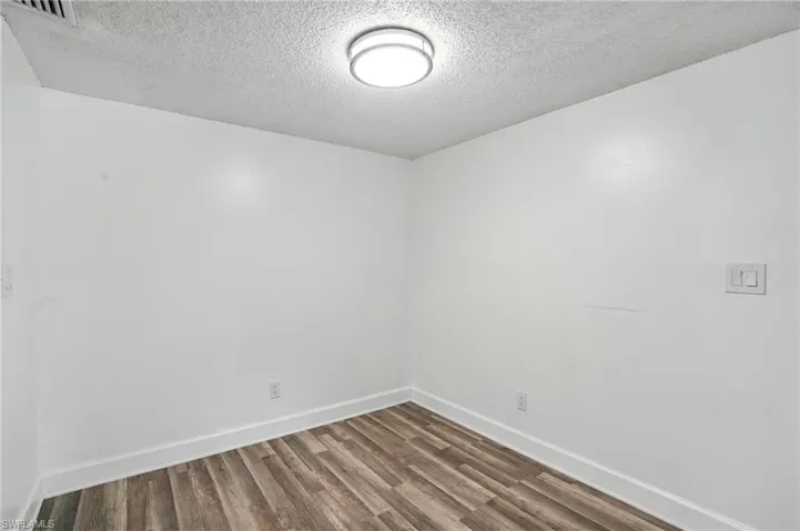 Unfurnished room with wood finished floors and a textured ceiling
