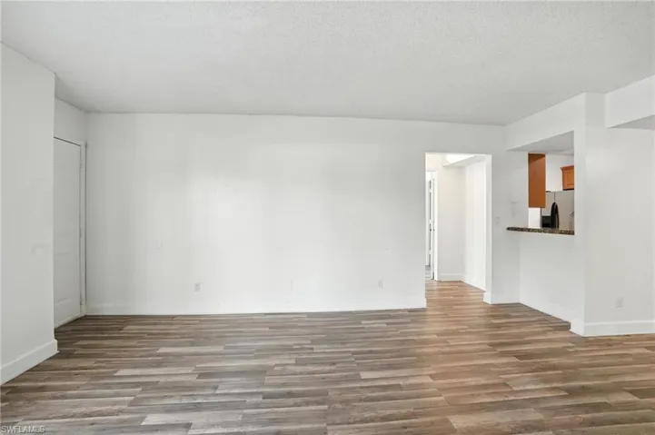 Unfurnished living room with wood finished floors and a textured ceiling