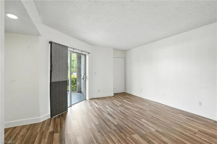 Empty room with wood finished floors, a textured ceiling, and recessed lighting
