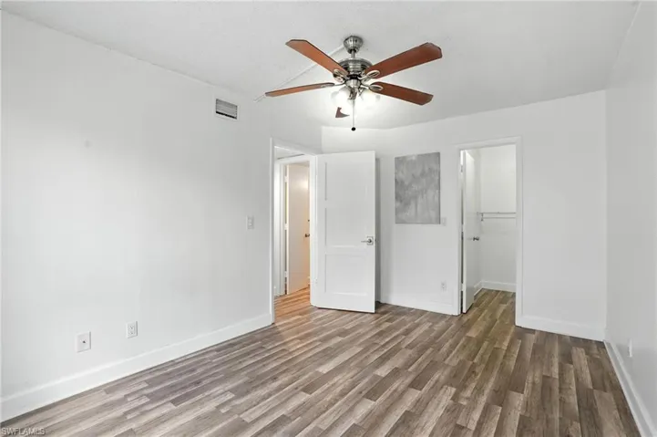 Unfurnished bedroom with wood finished floors, a spacious closet, a closet, and a ceiling fan