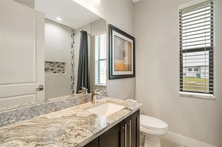 Bathroom with a shower with shower curtain, vanity, toilet, and a wealth of natural light