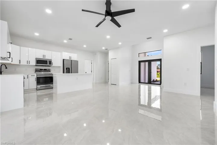 Unfurnished living room with sink, ceiling fan, and light tile floors