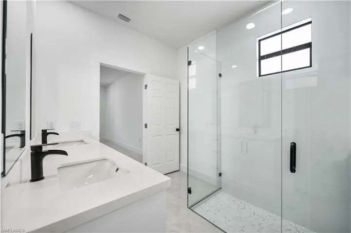 Bathroom featuring walk in shower, double sink vanity, and tile floors