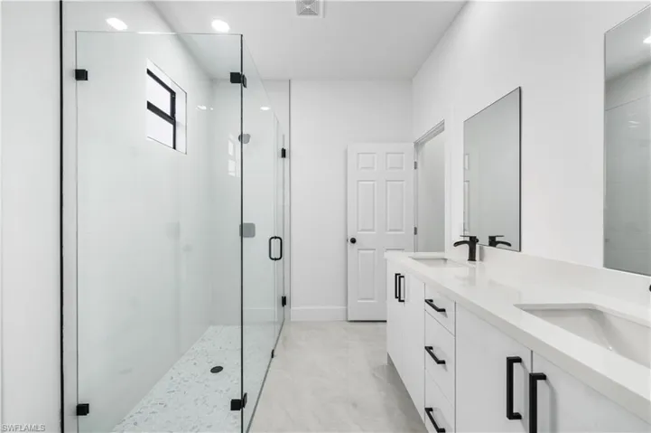 Bathroom featuring dual vanity, tile flooring, and a shower with door