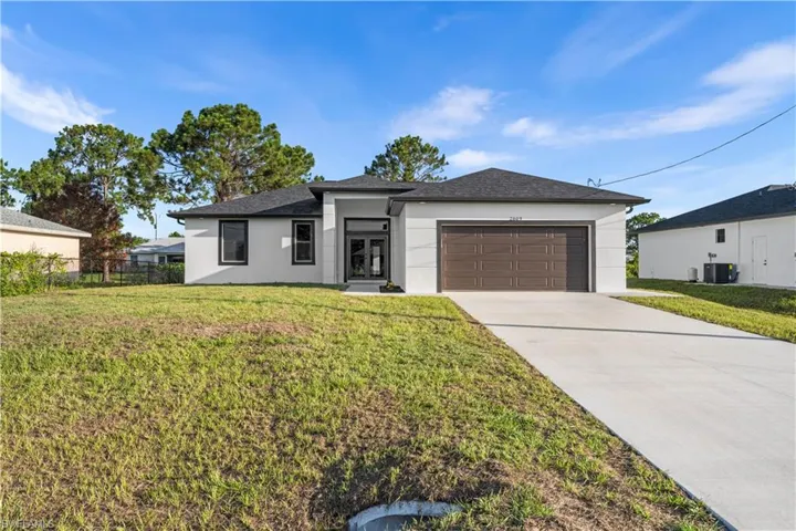 View of front of house with central AC, a front lawn, and a garage