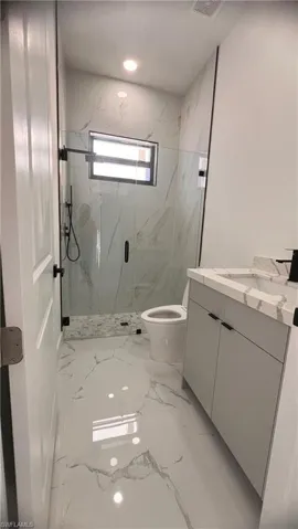 Bathroom with vanity, toilet, and a shower with shower door