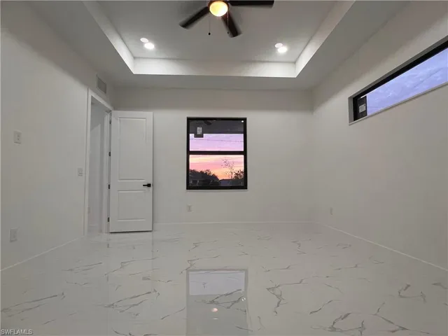 Unfurnished room with ceiling fan and a tray ceiling