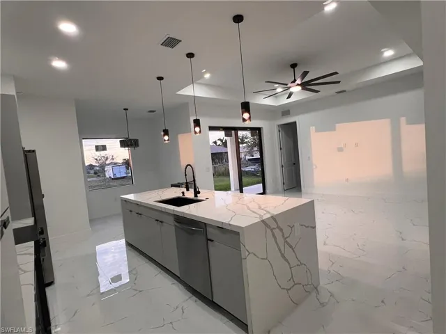 Kitchen featuring decorative light fixtures, plenty of natural light, a large island, and sink