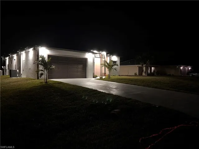 View of front of property with central AC, a garage, and a lawn