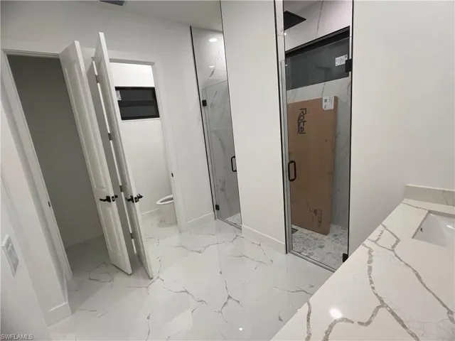 Bathroom featuring vanity, toilet, and an enclosed shower