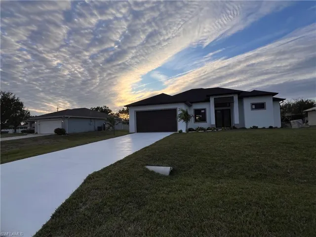 Single story home featuring a garage and a lawn
