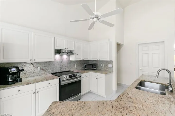 kitchen has granite counters, stainless appliances, white cabinetry