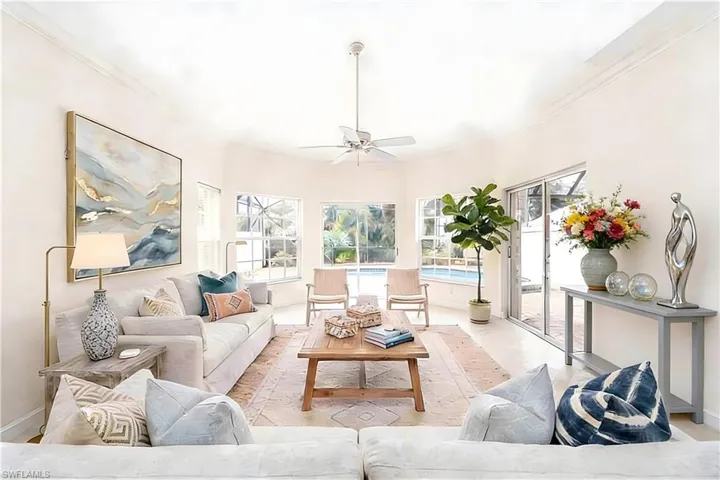 Spacious living area featuring high vaulted ceilings, crown molding, and light-tone tile flooring