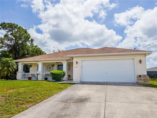 Ranch-style house with stucco siding, driveway, a porch, a front lawn, and an attached garage