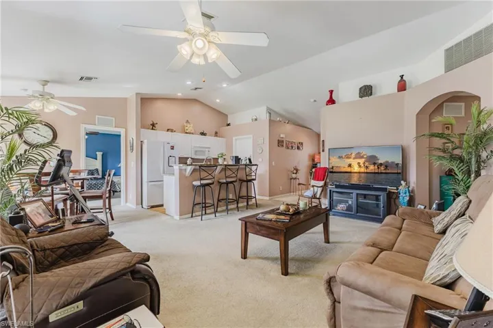 Living area featuring a ceiling fan, lofted ceiling, light carpet, recessed lighting, and baseboards
