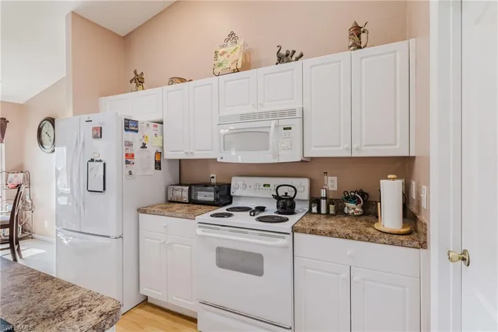 Kitchen featuring white appliances, white cabinets, and light wood-style flooring