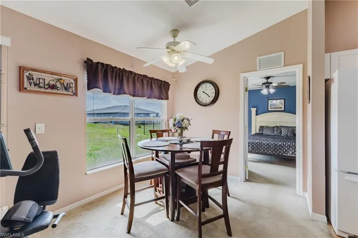 Dining space with light colored carpet, a ceiling fan, and baseboards