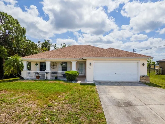 Ranch-style house featuring stucco siding, a porch, driveway, and a garage