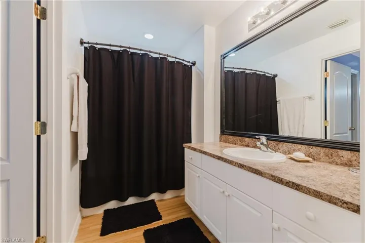 Full bathroom featuring vanity, wood finished floors, and a shower with curtain