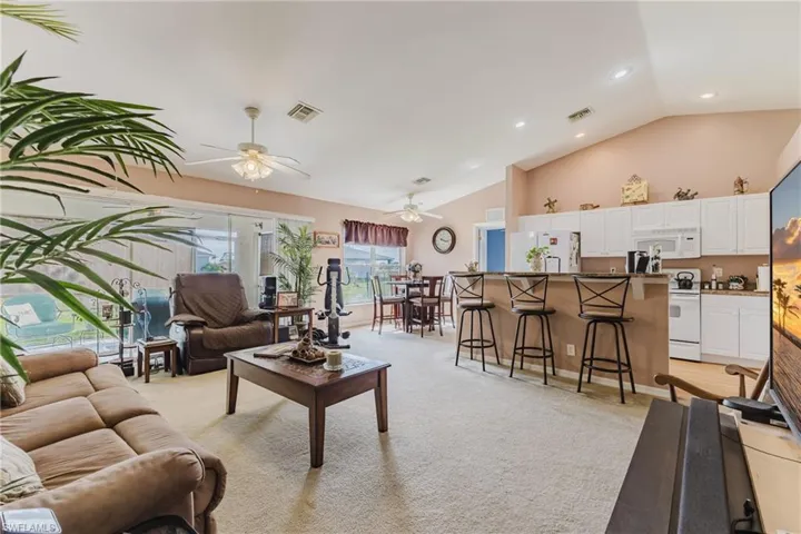 Living area featuring ceiling fan, light colored carpet, high vaulted ceiling, and recessed lighting