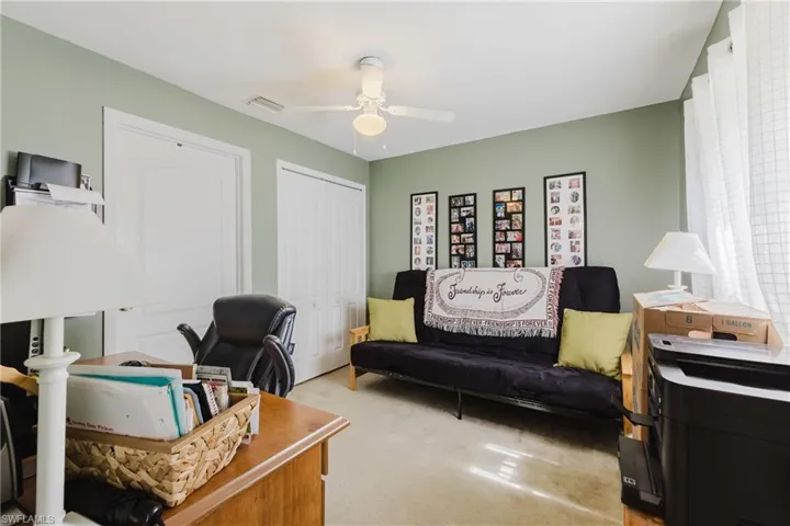 Office area with a ceiling fan and light carpet