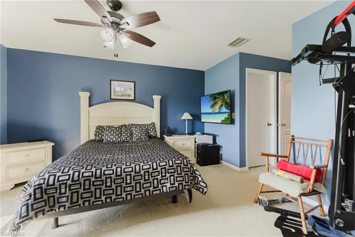 Carpeted bedroom featuring ceiling fan and baseboards