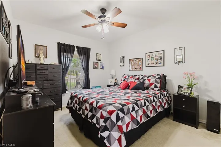 Bedroom with light colored carpet, a ceiling fan, and baseboards