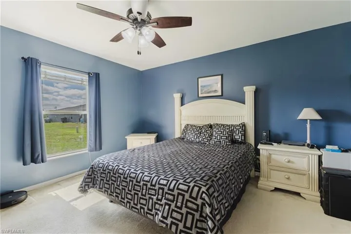 Carpeted bedroom with multiple windows, ceiling fan, and baseboards