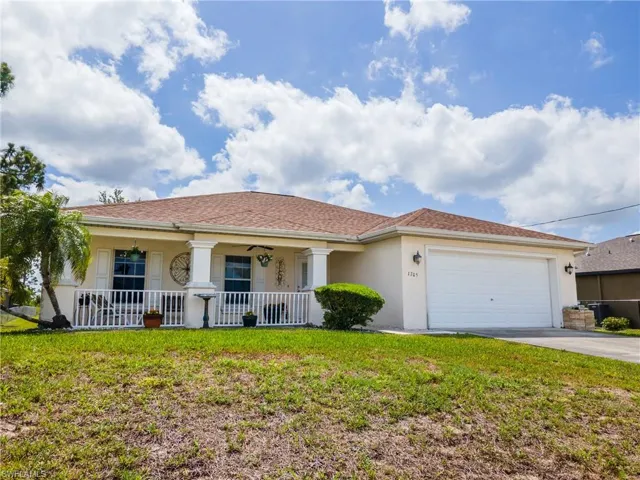 View of front of home featuring covered porch, stucco siding, driveway, a front yard, and a garage