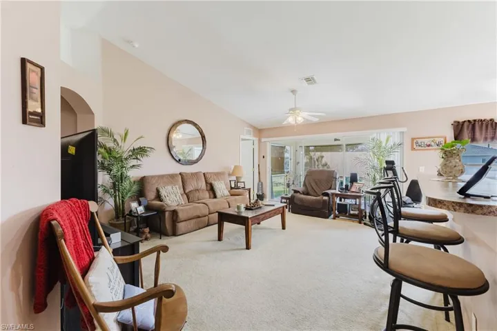 Carpeted living area featuring vaulted ceiling and a ceiling fan