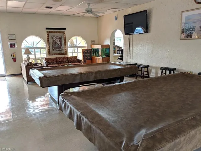 Recreation room featuring a textured wall, billiards table, a paneled ceiling, ceiling fan, and arched walkways