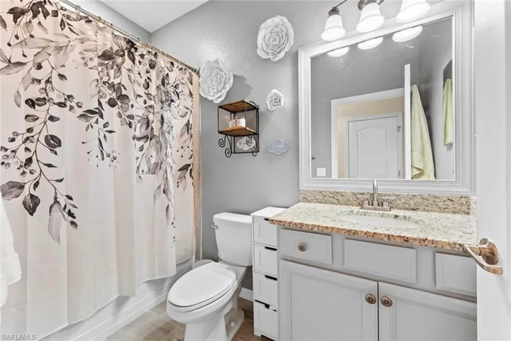Full bathroom with shower / tub combo with curtain, vanity, and toilet
